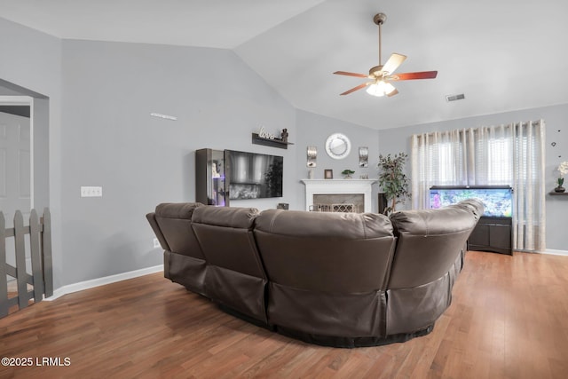 living room with baseboards, visible vents, wood finished floors, vaulted ceiling, and a fireplace