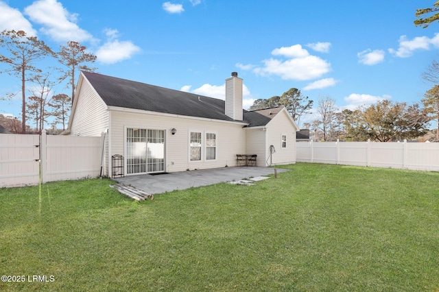 rear view of house with a fenced backyard, a yard, a gate, a chimney, and a patio area