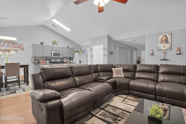 living room with lofted ceiling, visible vents, ceiling fan, and light wood-style flooring