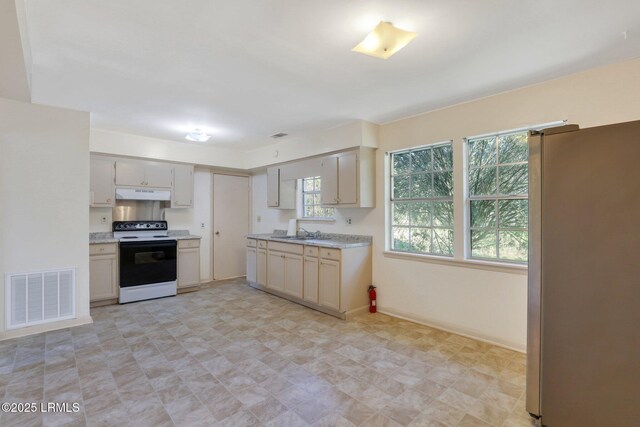 144 Middlefield Cir, Seabrook, SC 29940 - kitchen with visible vents, range with electric cooktop, under cabinet range hood, light countertops, and freestanding refrigerator