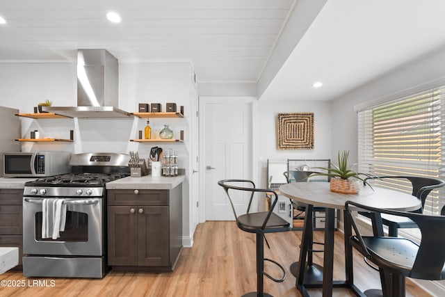 kitchen featuring wall chimney exhaust hood, appliances with stainless steel finishes, dark brown cabinets, and light hardwood / wood-style flooring