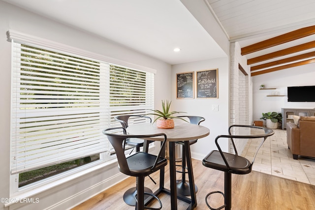 dining room with light hardwood / wood-style flooring and beamed ceiling