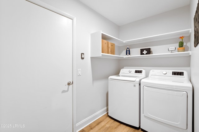 clothes washing area with washer and clothes dryer and light wood-type flooring