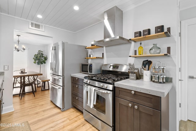 kitchen with wall chimney range hood, crown molding, dark brown cabinets, stainless steel appliances, and light wood-type flooring