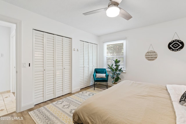 bedroom with ceiling fan, wood-type flooring, and multiple closets