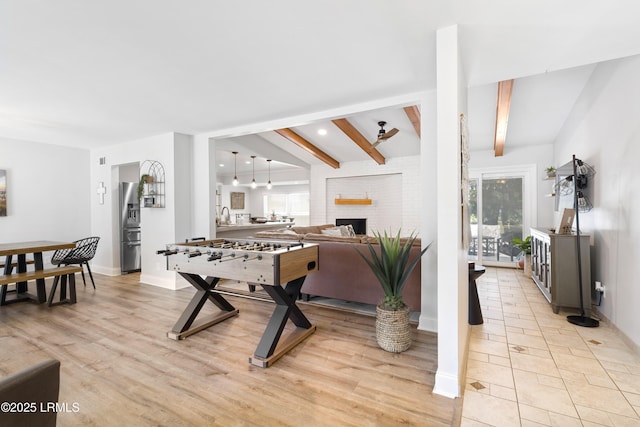 rec room with sink, beam ceiling, a fireplace, and light wood-type flooring