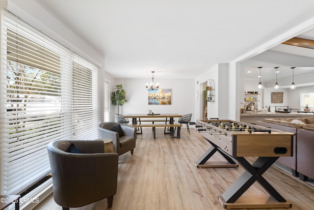 rec room with light hardwood / wood-style flooring and a chandelier