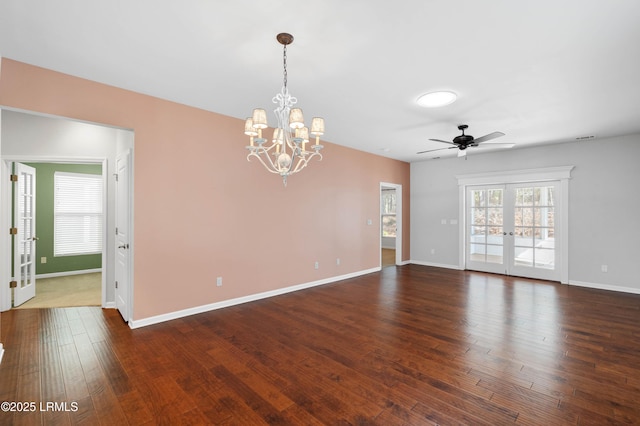 spare room featuring ceiling fan with notable chandelier, dark wood-type flooring, and french doors