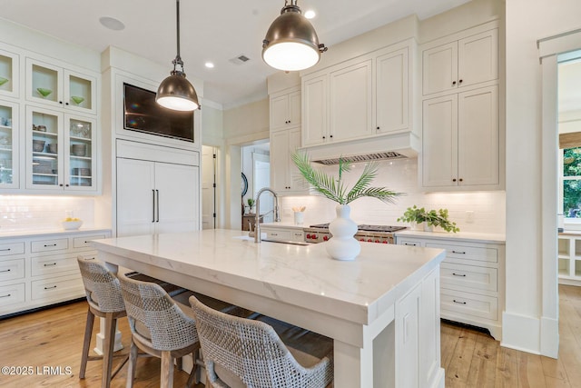 24 Carrier Blf, Bluffton, SC 29909 - kitchen featuring under cabinet range hood, tasteful backsplash, a breakfast bar, light stone counters, and white cabinets