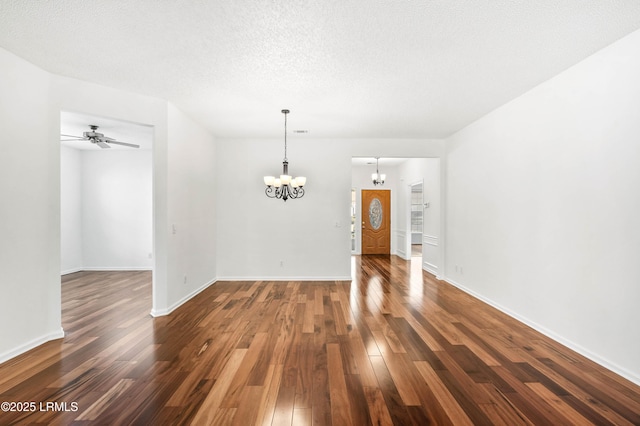 unfurnished room featuring dark wood-type flooring, ceiling fan with notable chandelier, and a textured ceiling