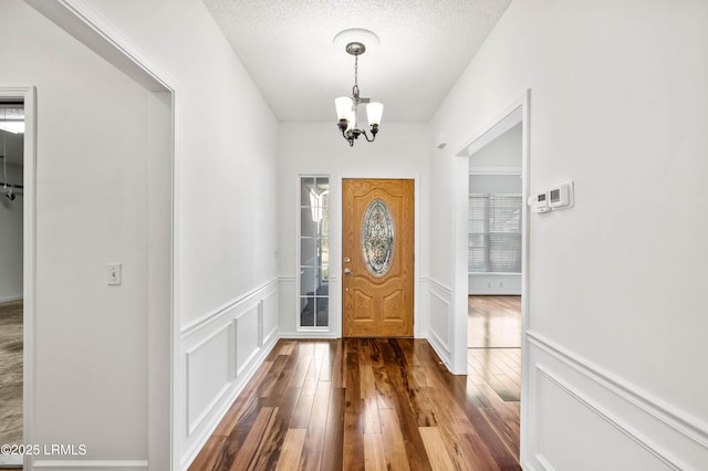 foyer with an inviting chandelier, hardwood / wood-style floors, and a textured ceiling