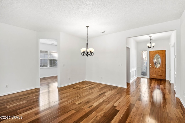 entrance foyer featuring an inviting chandelier, hardwood / wood-style flooring, and a textured ceiling