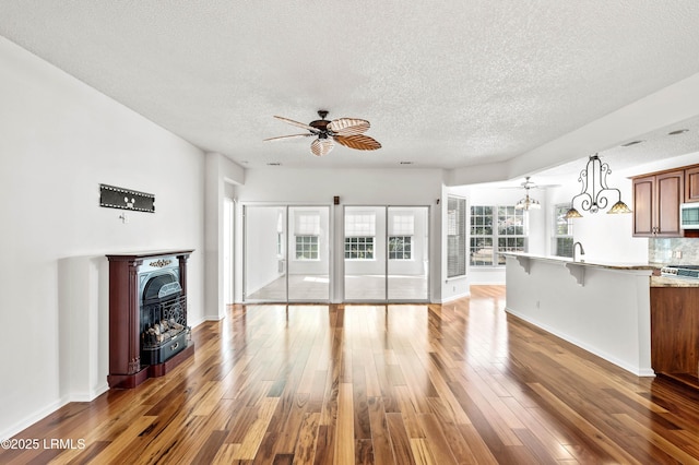 unfurnished living room featuring dark hardwood / wood-style flooring, sink, a fireplace, and ceiling fan