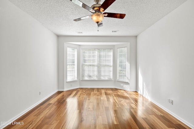 spare room with ceiling fan, light hardwood / wood-style floors, and a textured ceiling