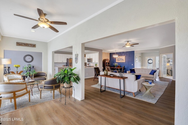 living area with a ceiling fan, wood finished floors, and ornamental molding