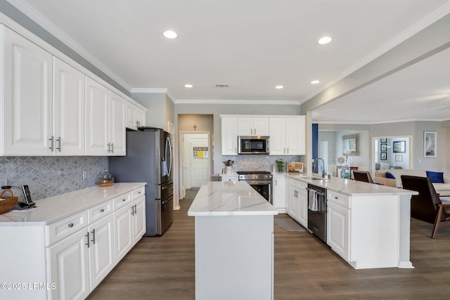 kitchen featuring open floor plan, appliances with stainless steel finishes, a peninsula, dark wood-style floors, and a sink