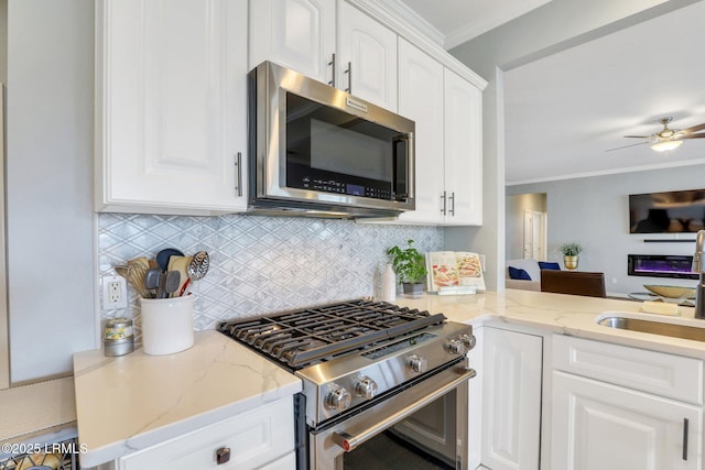 kitchen with tasteful backsplash, crown molding, light stone countertops, appliances with stainless steel finishes, and white cabinetry