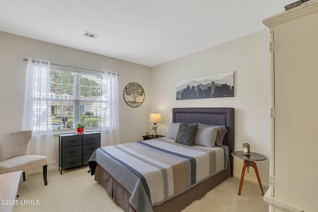 bedroom with a textured ceiling, baseboards, visible vents, and light carpet