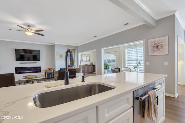 kitchen featuring visible vents, a sink, open floor plan, white cabinetry, and light stone countertops