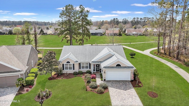 view of front facade featuring a residential view, a front yard, stucco siding, decorative driveway, and a garage