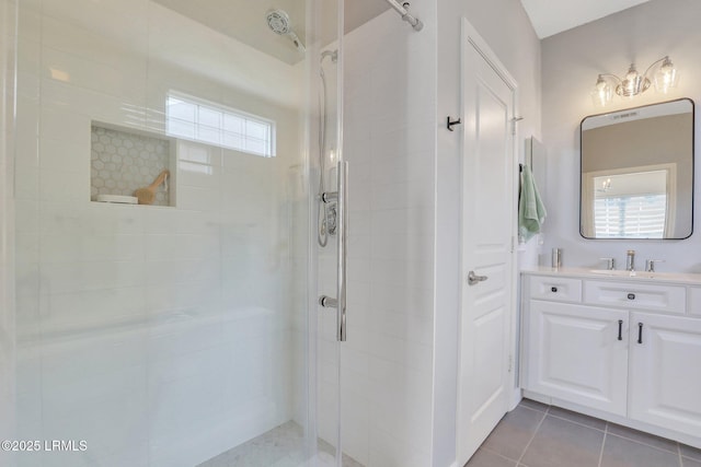 full bath with vanity, tile patterned flooring, and a tile shower