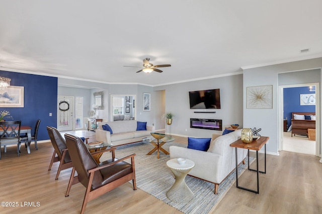 living area featuring baseboards, ceiling fan with notable chandelier, crown molding, and light wood finished floors