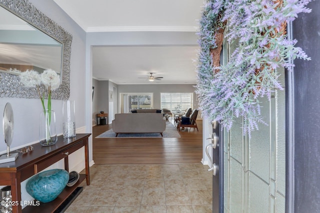 entrance foyer with light tile patterned flooring, ceiling fan, and ornamental molding