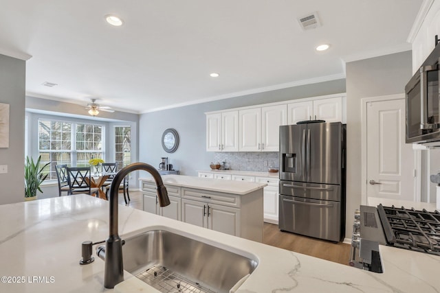 kitchen with visible vents, a sink, ceiling fan, stainless steel appliances, and white cabinets