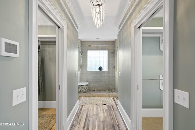 hallway with an inviting chandelier, ornamental molding, and wood-type flooring