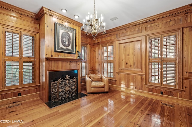 living area with ornamental molding, a chandelier, and wood walls