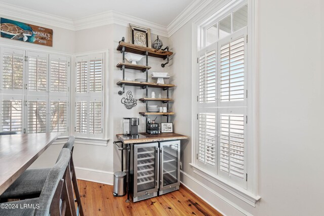 interior space with bar, crown molding, light hardwood / wood-style flooring, and beverage cooler