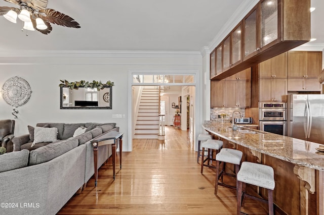 living room with sink, light hardwood / wood-style flooring, ornamental molding, and ceiling fan