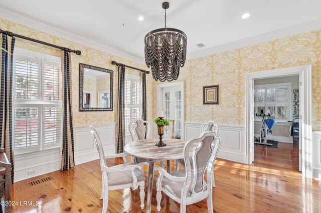 dining area with an inviting chandelier, crown molding, and light hardwood / wood-style floors