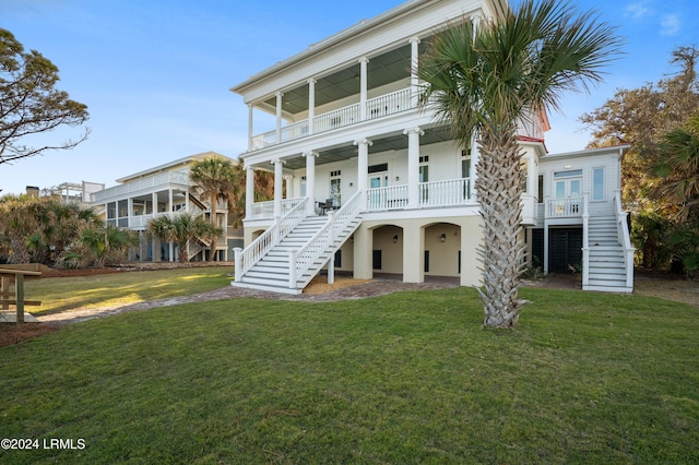 coastal inspired home with a balcony, a porch, and a front lawn