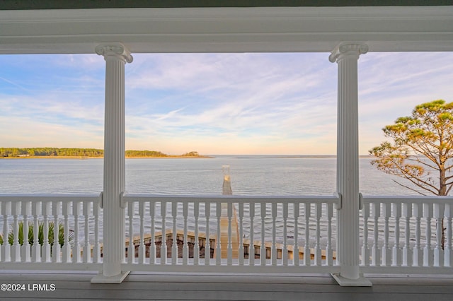 deck at dusk featuring a water view