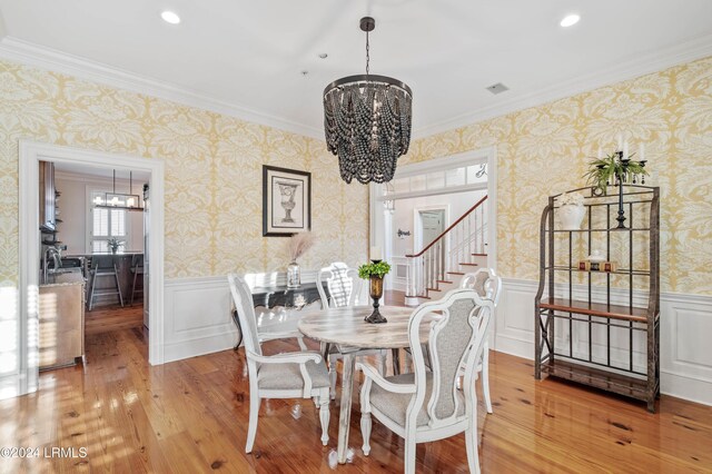 dining room with ornamental molding, an inviting chandelier, and light hardwood / wood-style flooring