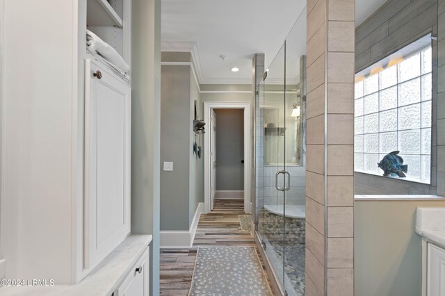 bathroom featuring hardwood / wood-style flooring, ornamental molding, a healthy amount of sunlight, and an enclosed shower