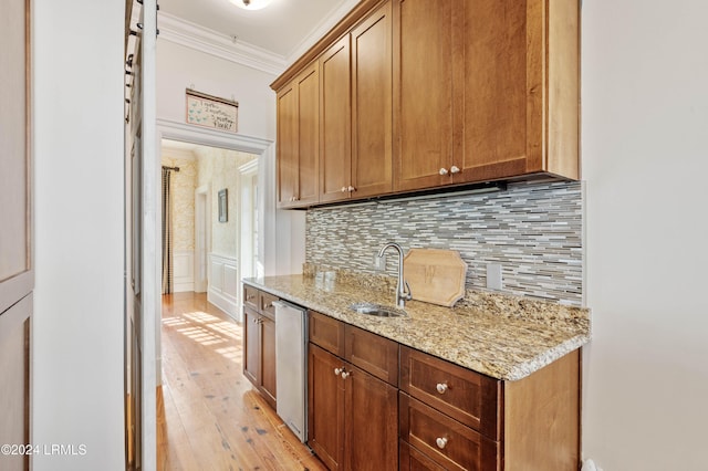 kitchen featuring crown molding, dishwasher, sink, and light stone counters