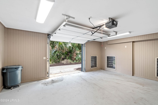 garage featuring a garage door opener and wooden walls