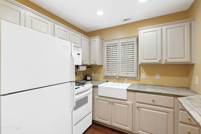 kitchen with white cabinetry, sink, white appliances, and tile countertops