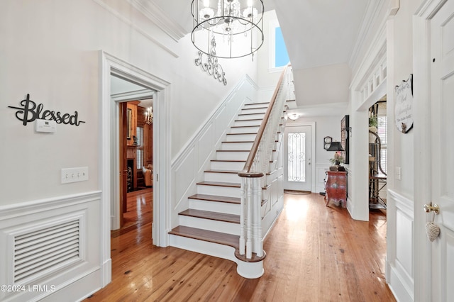 entryway with an inviting chandelier, light hardwood / wood-style flooring, and ornamental molding