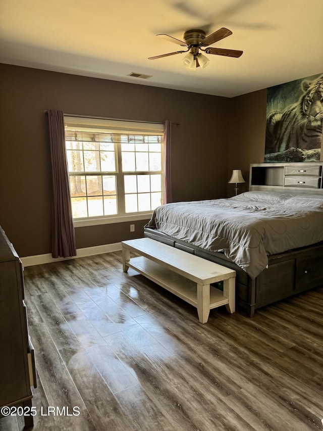 bedroom featuring ceiling fan, visible vents, baseboards, and wood finished floors