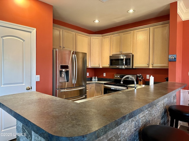 kitchen with a breakfast bar, a peninsula, recessed lighting, appliances with stainless steel finishes, and dark countertops