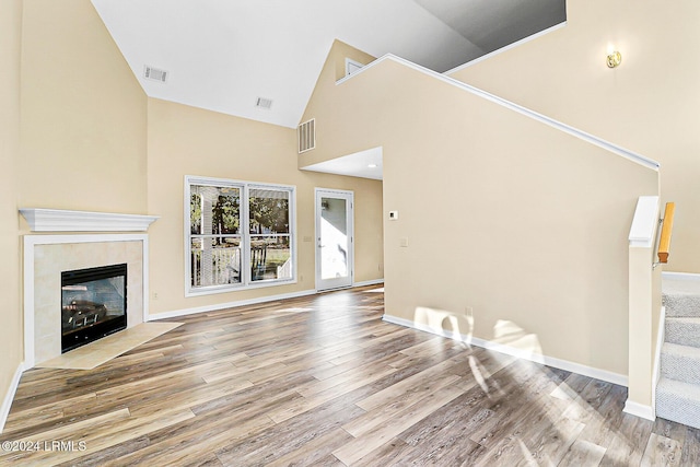 unfurnished living room with stairs, a tile fireplace, wood finished floors, and visible vents