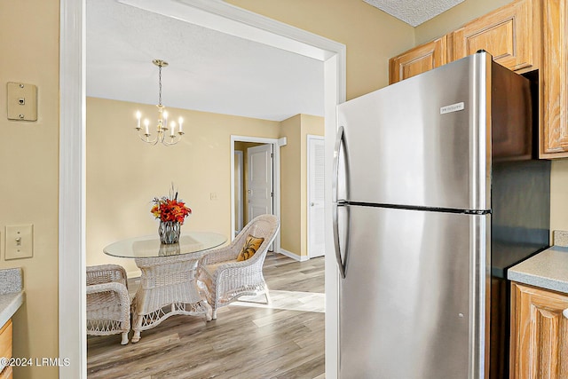 kitchen with freestanding refrigerator, light countertops, light wood-style floors, a chandelier, and pendant lighting