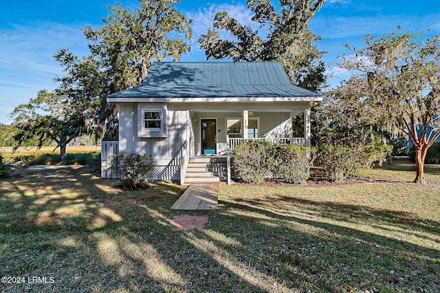 bungalow-style house with a porch, metal roof, a standing seam roof, a front lawn, and board and batten siding