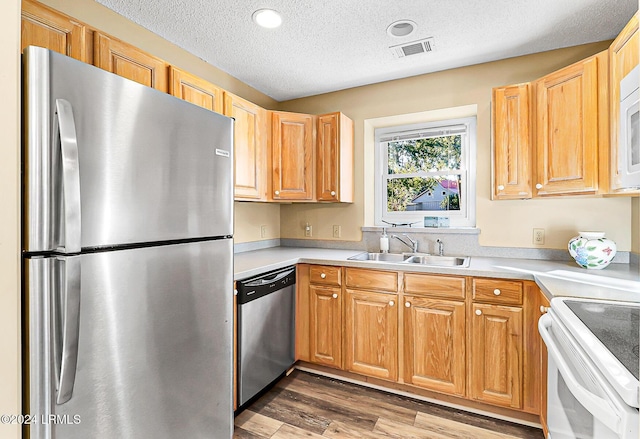 kitchen with light countertops, visible vents, appliances with stainless steel finishes, a sink, and wood finished floors