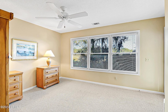 bedroom featuring visible vents, light colored carpet, a ceiling fan, a textured ceiling, and baseboards