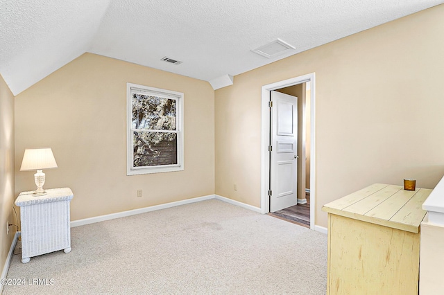 interior space with baseboards, visible vents, vaulted ceiling, a textured ceiling, and carpet floors