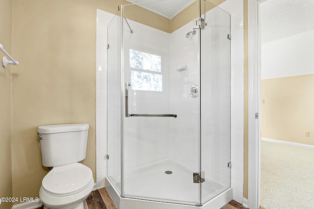 bathroom with baseboards, a shower stall, and toilet